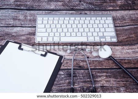 Medical Concept : Stethoscope with clipboard and keyboard on wooden background.