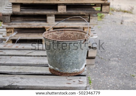 an old iron bucket in the garden at wooden pallet / an old rusty bucket / Old galvanised bucket / Royalty-Free Stock Photo #502346779