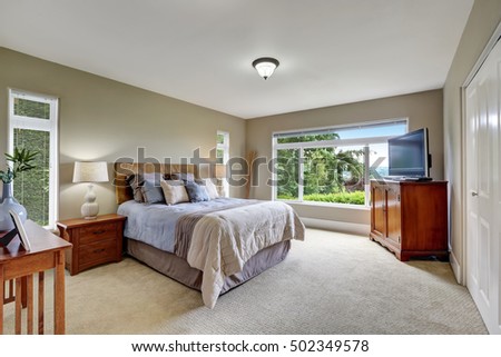 Elegant bedroom interior with soft blue bed and television on the top of the cabinet. Northwest, USA