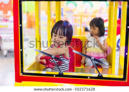 Asian Chinese Little Sister Driving Toy Bus at indoor playground.