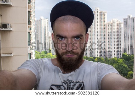 Funny man with a beard.A guy in a big city with big houses