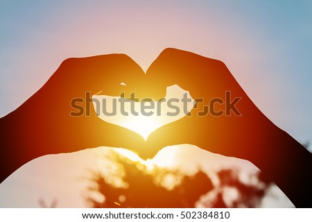 love shape hand silhouette at sunset background