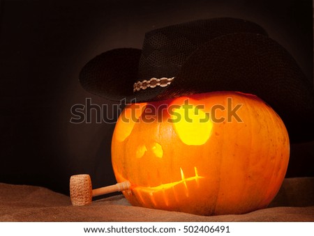 Pumpkin on Halloween in a cowboy hat with a pipe on an black background