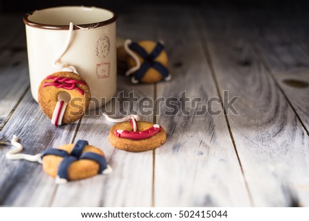cookies with a life preserver decoration; the focus is on the biscuit leaning against a cup. Horizontal picture with copy space