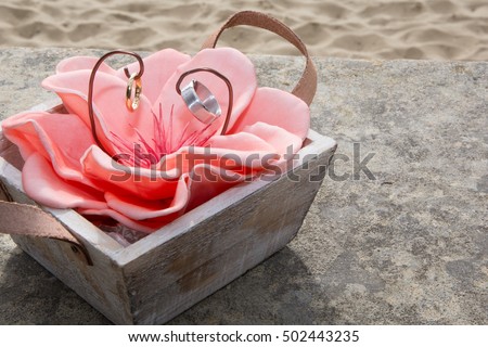 pair of wedding rings and roses on the beach, macro shot.
