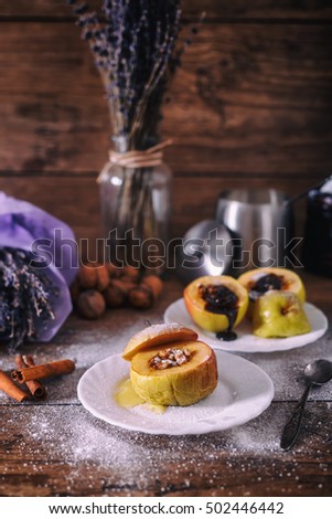stuffed baked apple with nuts, honey and chocolate on white dessert plates, dark wooden background. Christmas sweet. healthy eating concept.