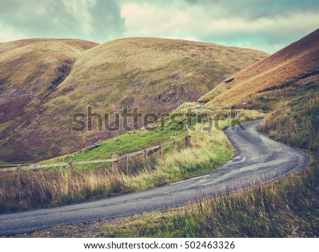 Winding Single Lane Road Up Through The Rugged Landscape Of The Scottish Borders Royalty-Free Stock Photo #502463326