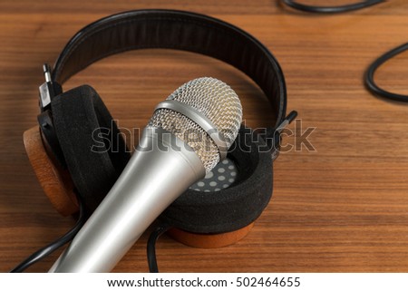 Elegant headphones and a studio microphone on a wooden table. Tools for vocals