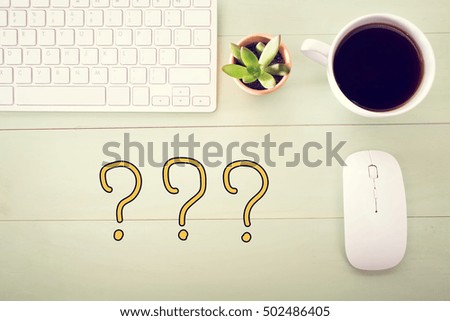 Question Mark concept with workstation on a light green wooden desk