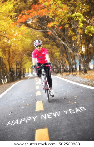 Word of Happy New Year on road surface with sportswoman on countryside with tree tunnel