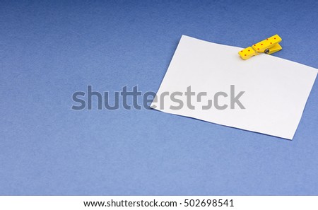 a blank card with space for notes on the wooden clothespin colored paper on blue background mock up