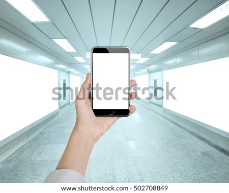 Woman hand holding smart phone with blank white screen in underpass background, front view.