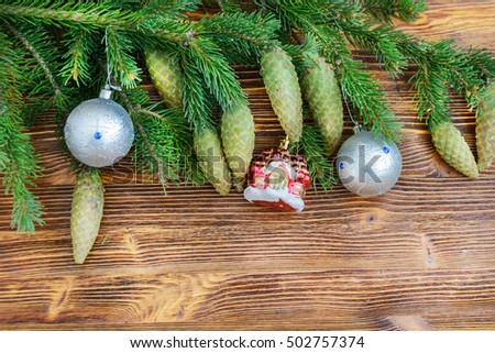 Christmas decorative background. Fur-tree branch with cones and Christmas balls on a wooden background.