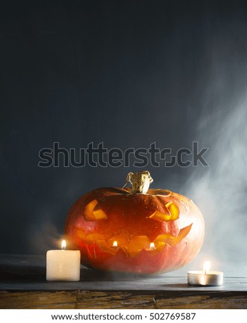 Halloween pumpkin with candles and smoke on a dark background