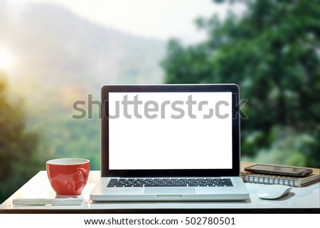 Front view of cup and laptop on table in Office park and blurred background of trees in the forest