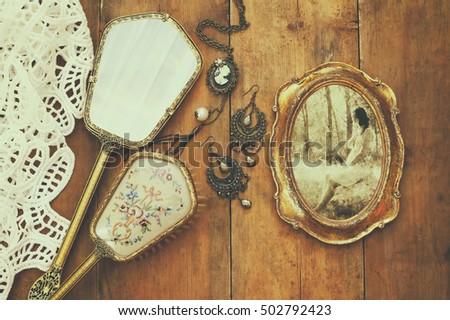 Top view image of vintage woman toilet fashion objects next to photo frame with photography of beautiful woman on old wooden table
