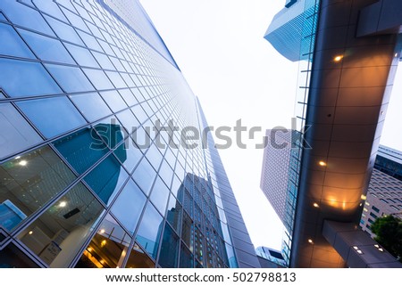 Business concept for real estate and corporate construction - looking up view in financial district, the silhouettes of skyscrapers city reflect dramatic blue sky, sun lights in Tokyo, Japan