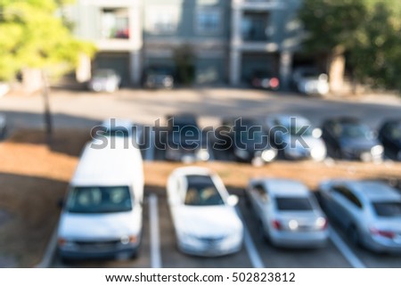 Abstract blurred elevated view of apartment garage with full of covered parking, cars and green trees at multi-floor residential buildings in Houston, Texas, US. Aerial view of crowded parking lot.