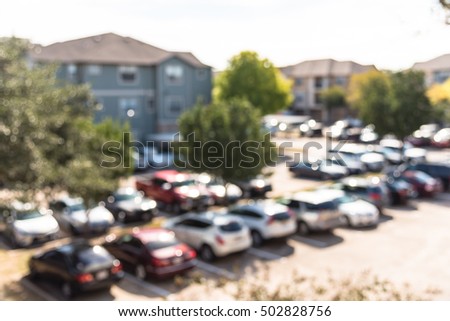 Abstract blurred elevated view of apartment garage with full of covered parking, cars and green trees at multi-floor residential buildings in Houston, Texas, US. Aerial view of crowded parking lot.