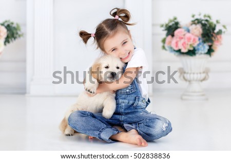 child with little dogs playing at home. girl with puppies. chid with puppy. kissing, hugging, playing in room