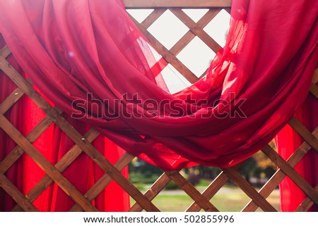 A fragment of a wooden wedding arch with a red fabric