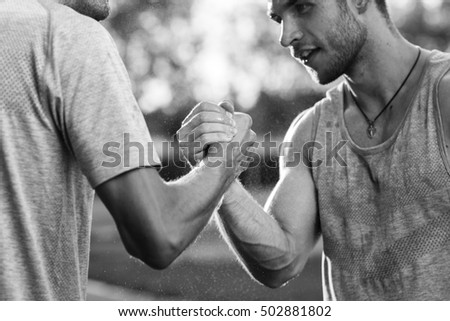 Black-and-white photograph of arms with muscles handshake