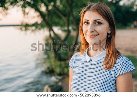 Young smiling woman near lake in dusk. 