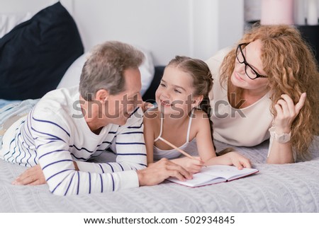Smiling girl drawing and having fun with her grandparents