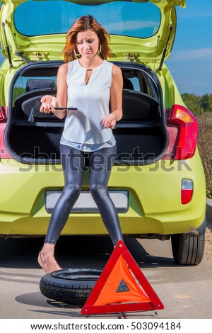 girl with a spare wheel and tools near the car