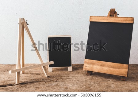 wooden easel with black board on wooden background