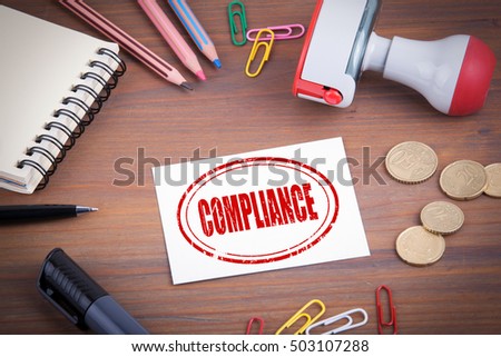 Compliance stamp. Wooden office desk with stationery, money and a note pad