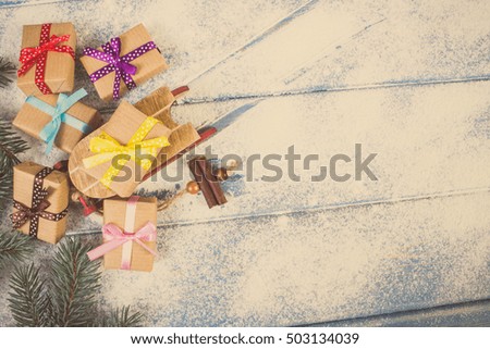 Spruce branches and wooden sled with wrapped colorful gifts for Christmas or other celebration, copy space for text or inscription on old boards with snow