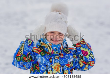 Portrait of a little girl in a ski suit. It is a walk in the winter cold day. She froze.
