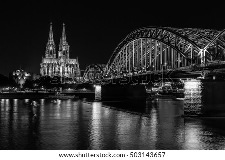 Cologne Cathedral and Hohenzollern Bridge at nighttime. ( black and white photo )
