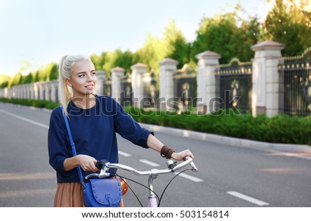 Young woman with bicycle in park on blurred background
