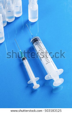 Medical ampoules and syringes over blue background. Pro vaccine concept. Useful for medical, pharmaceutical background.