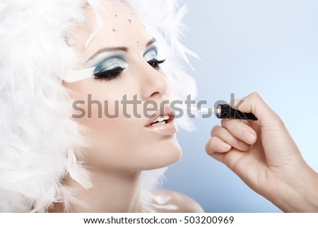 Last steps of applying professional winter makeup on beautiful model, applying lipstick.