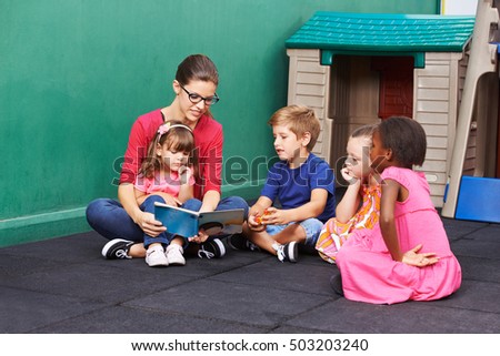 Nursery woman reading book for group of children in a kindergarten