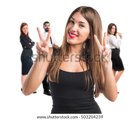 Girl doing victory gesture with many people behind
