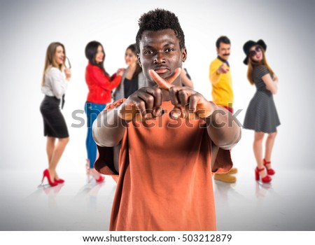 Handsome black man doing NO gesture with many people behind