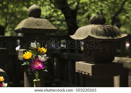 Closeup of two stone pagodas and flower decoration at a small memorial of a Shinto priest in the ueno park in Tokyo, Japan. Picture taken on 15 May 2016.