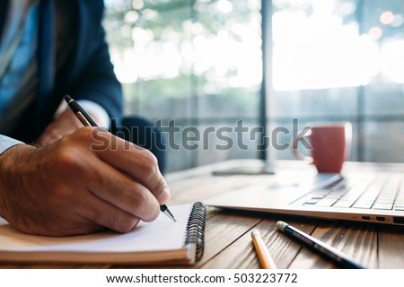Male hand taking notes on the notepad. Handwriting. Creative writing. Inscription or recording of signs and symbols. Royalty-Free Stock Photo #503223772