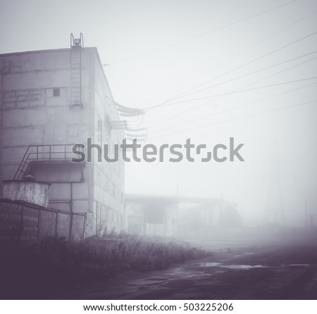 Industrial area. Old, blur, defective, monochrome photo.. Foggy autumn weather. Factory with high voltage wires.