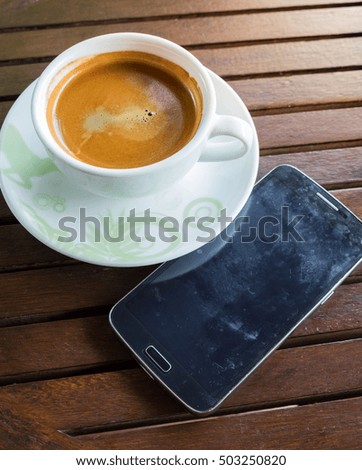 Hot coffee with the old-mobile phone on the wood table in the morning.