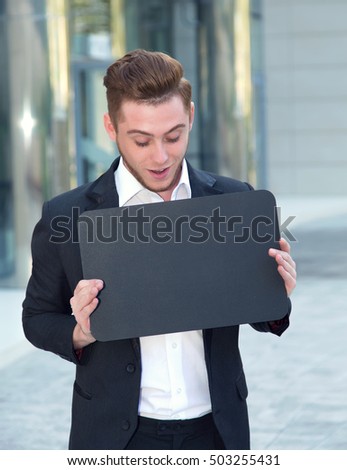 Young businessman shows on the display. Space for text.