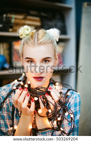Portrait of a young woman with lights. beautiful girl with white hair dyed, holding christmas lights