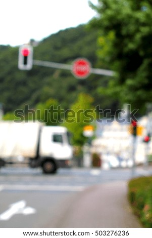 Abstract high key blurred image of crossroad with red light. White truck crossing the road.