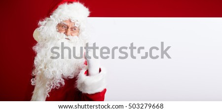 Santa Claus pointing in blank advertisement banner isolated on red background with copy space