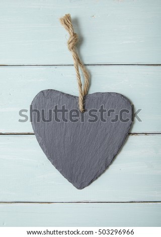 A rustic slate heart gift tag on a blue wooden background