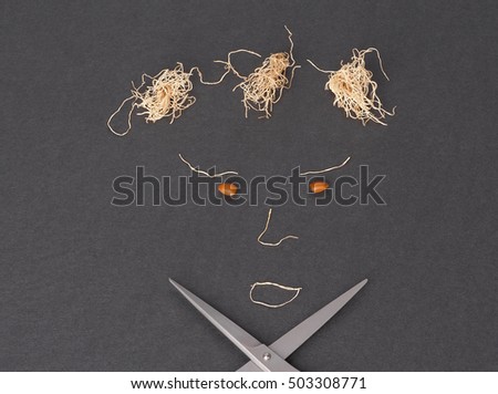 a picture of a face made with carob seeds, garlic roots and scissors on black background